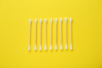 Photo of Many wooden cotton buds on yellow background, flat lay