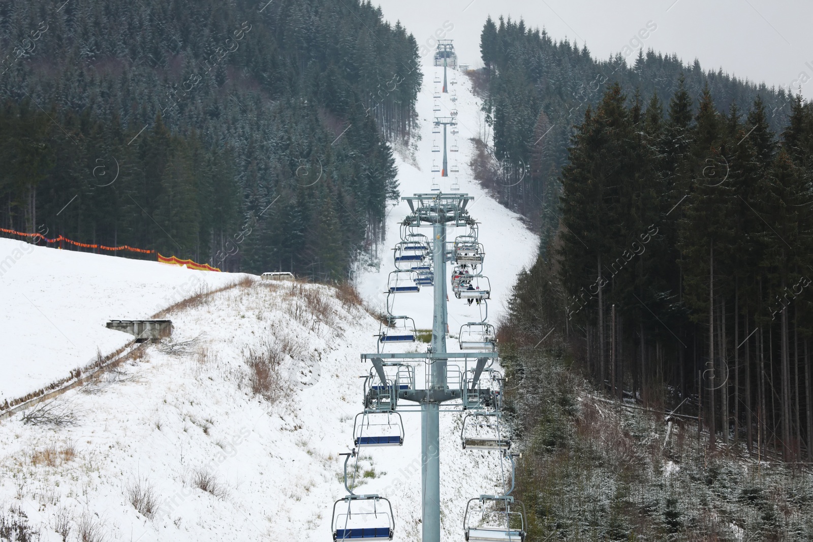 Photo of Chairlift with people at ski resort. Winter vacation