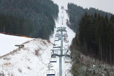 Photo of Chairlift with people at ski resort. Winter vacation