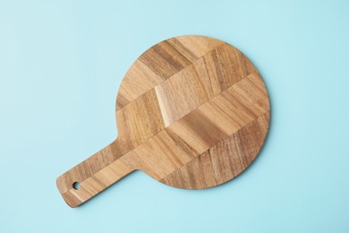 Photo of One wooden board on light blue background, top view