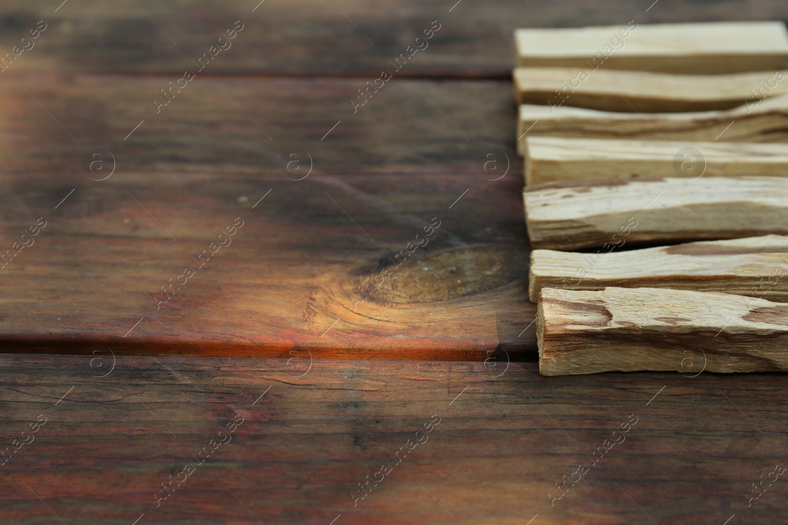 Photo of Palo santo sticks on wooden table, space for text