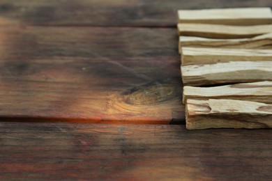 Photo of Palo santo sticks on wooden table, space for text