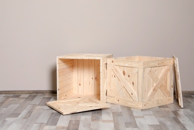 Photo of Wooden crates on floor at beige wall. Space for text