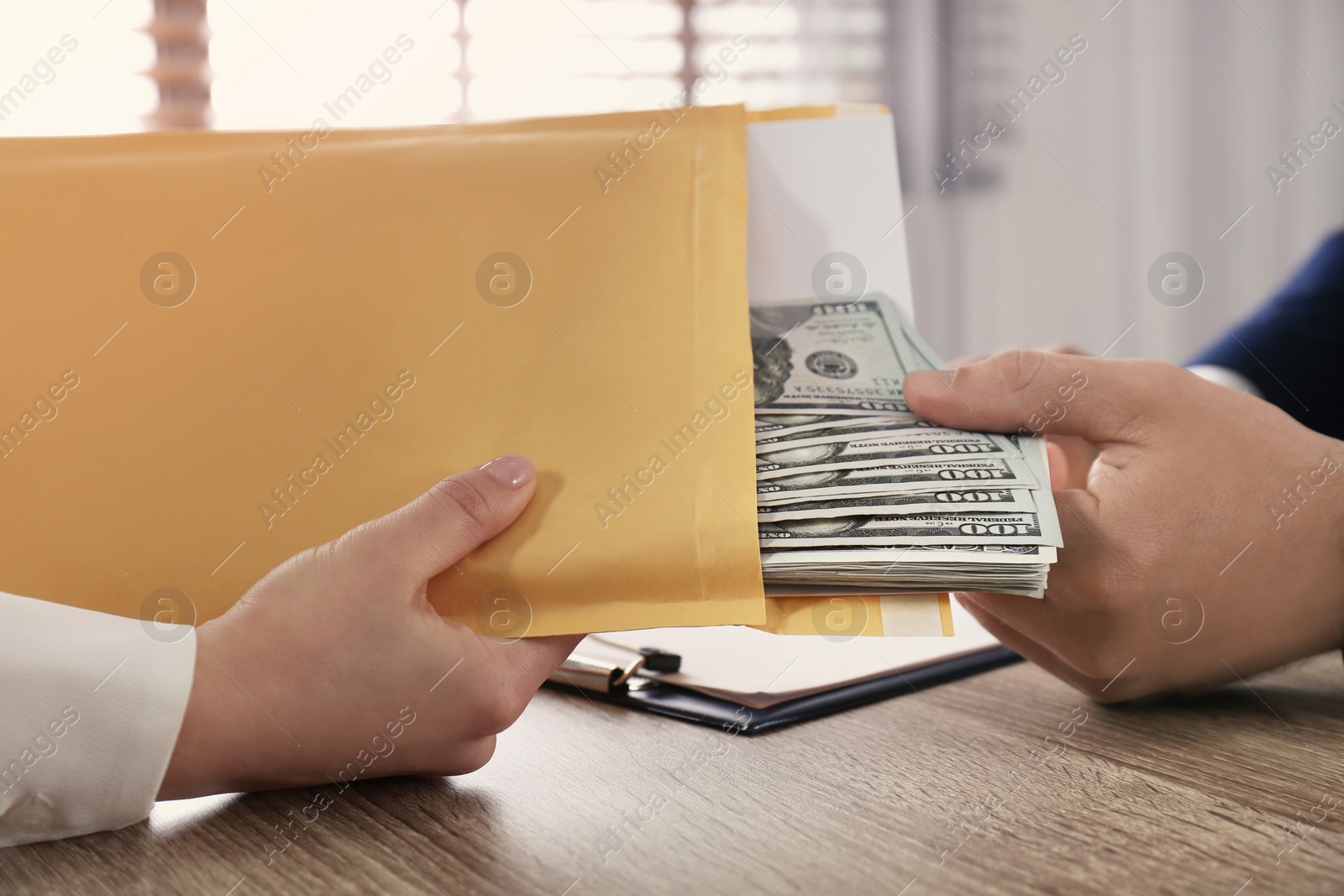 Photo of Woman giving bribe to man at table in office, closeup