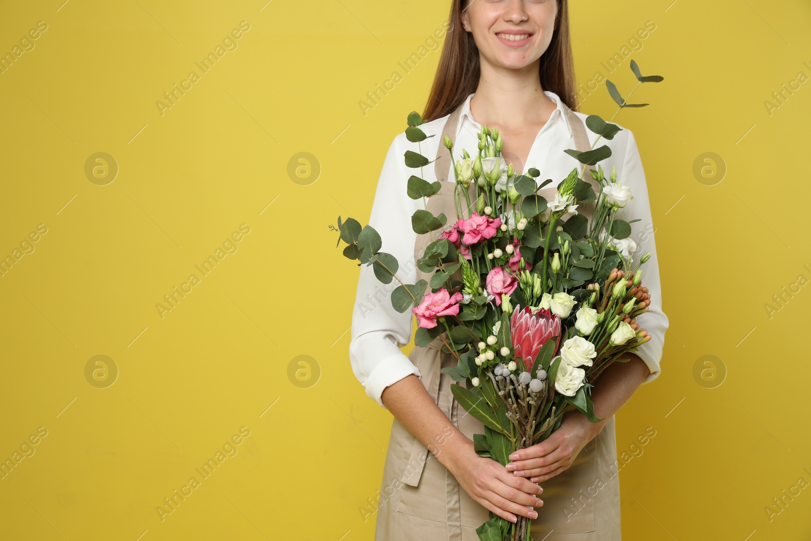 Photo of Florist with beautiful bouquet on yellow background, closeup. Space for text