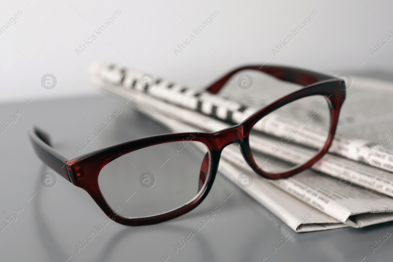 Photo of Newspapers and glasses on grey table, closeup