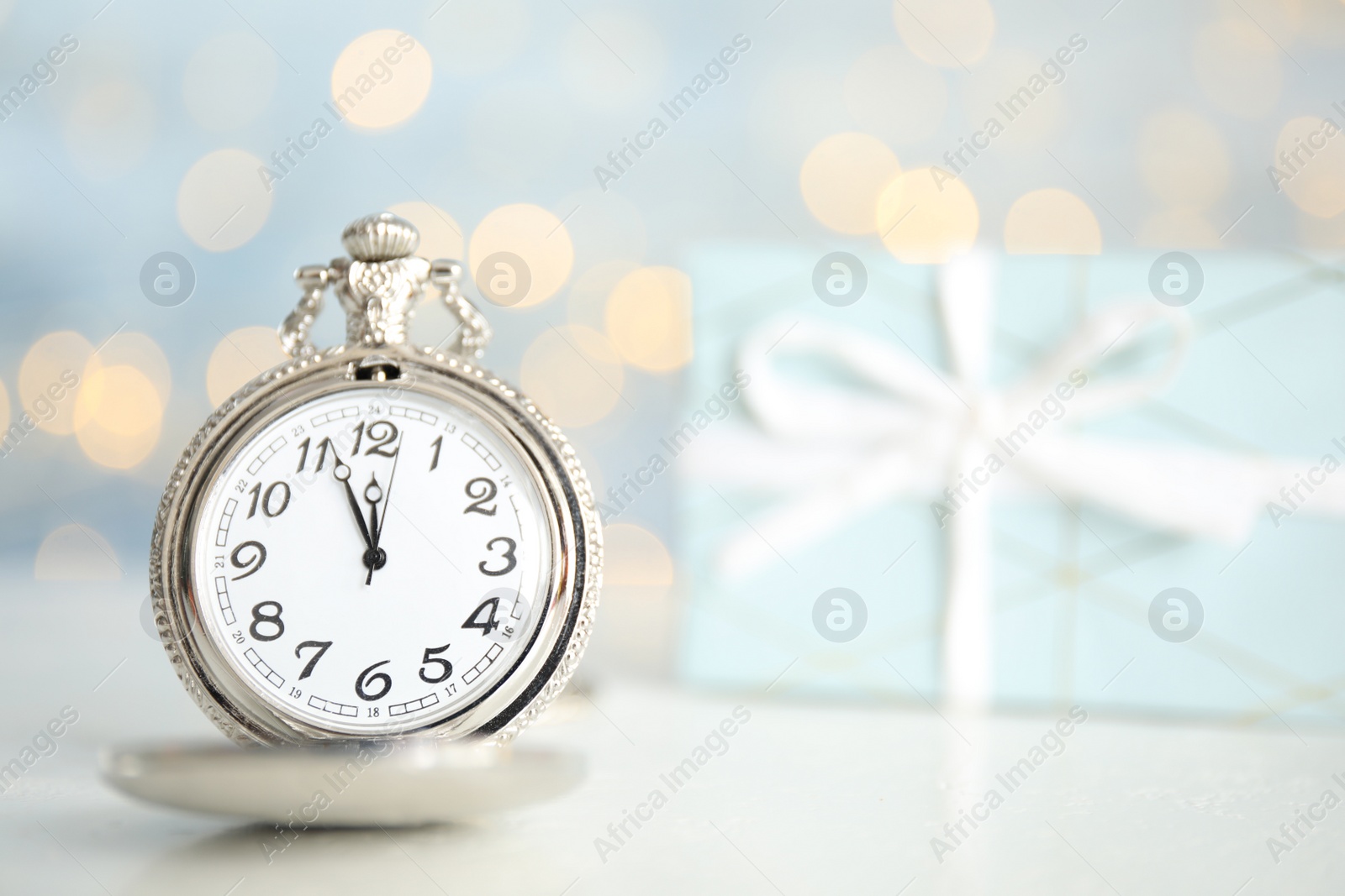 Photo of Pocket watch on table against blurred lights, space for text. New Year countdown