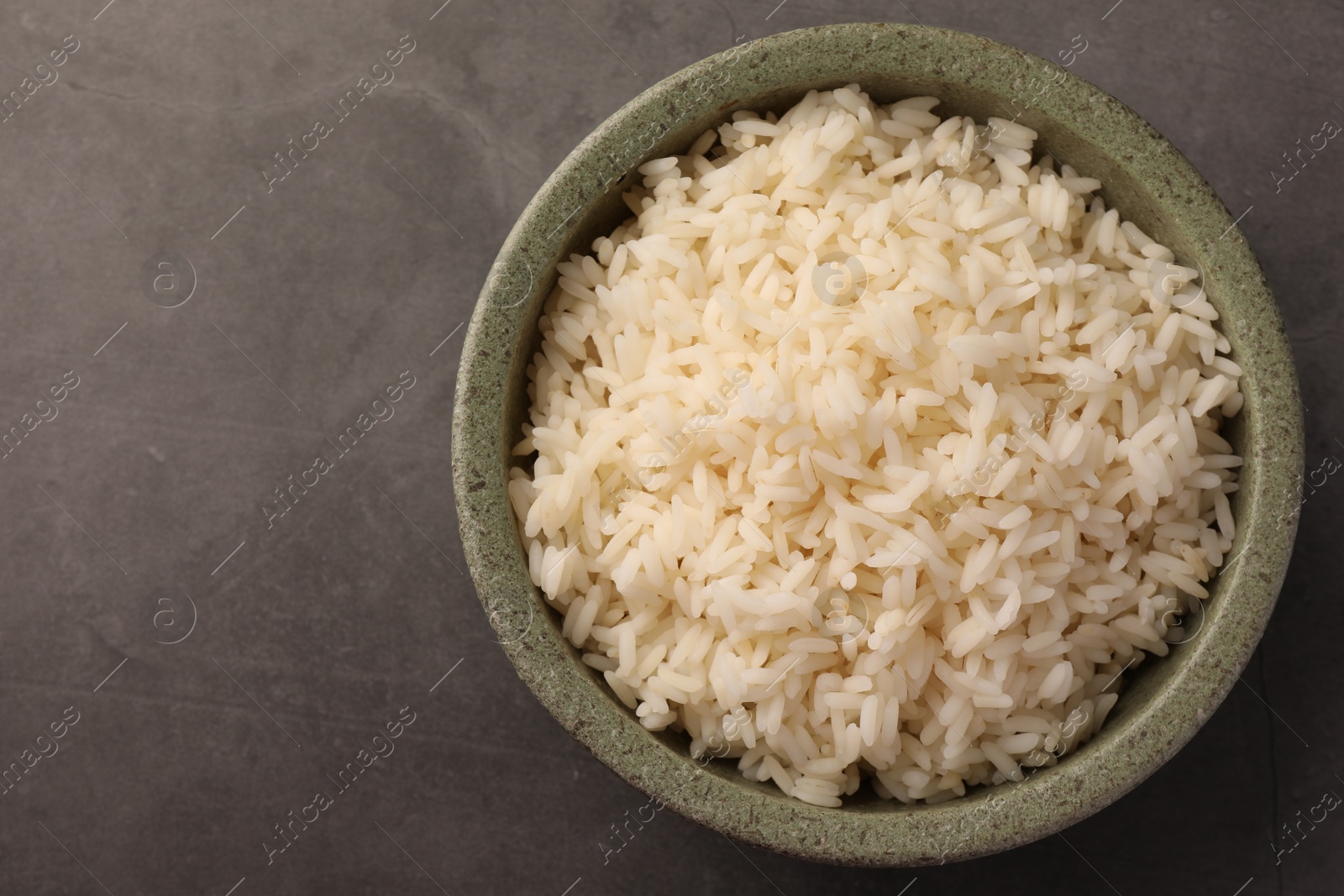 Photo of Delicious rice in bowl on grey table, top view. Space for text