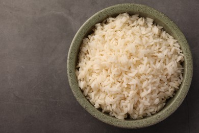 Photo of Delicious rice in bowl on grey table, top view. Space for text