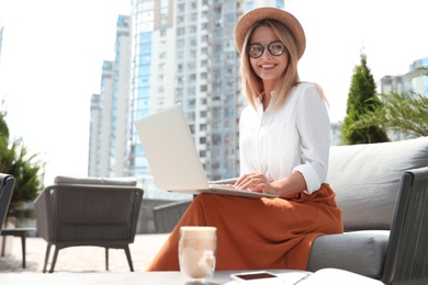 Photo of Beautiful woman using laptop at outdoor cafe