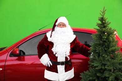 Photo of Authentic Santa Claus near car with fir tree against green background