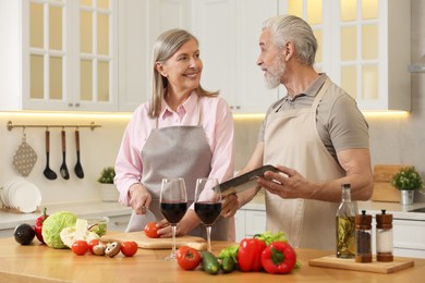 Happy senior couple cooking together in kitchen