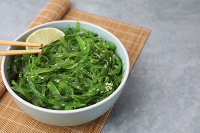 Photo of Tasty seaweed salad in bowl served on gray table, closeup