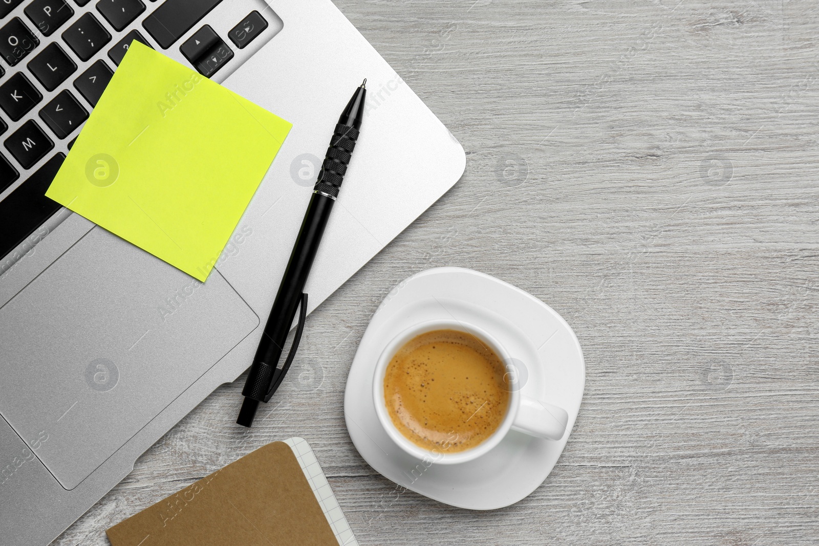 Photo of Laptop with blank sticky note, pen and cup of coffee  on white wooden table, flat lay. Space for text