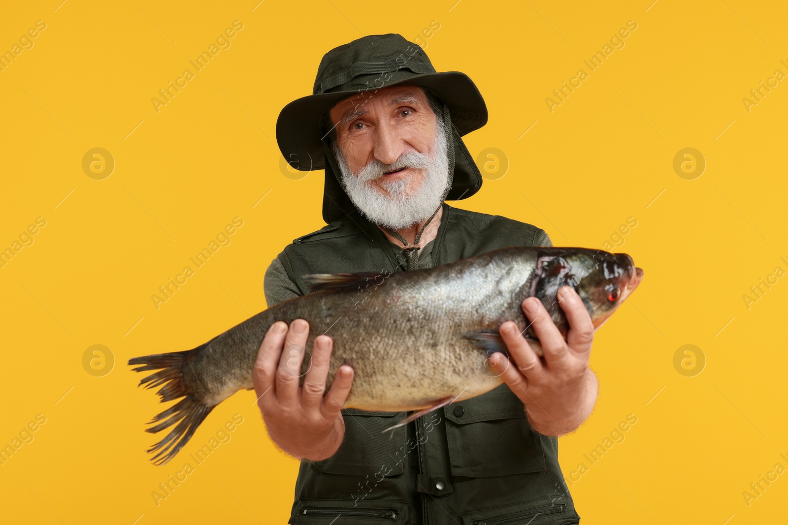 Photo of Fisherman with caught fish on yellow background