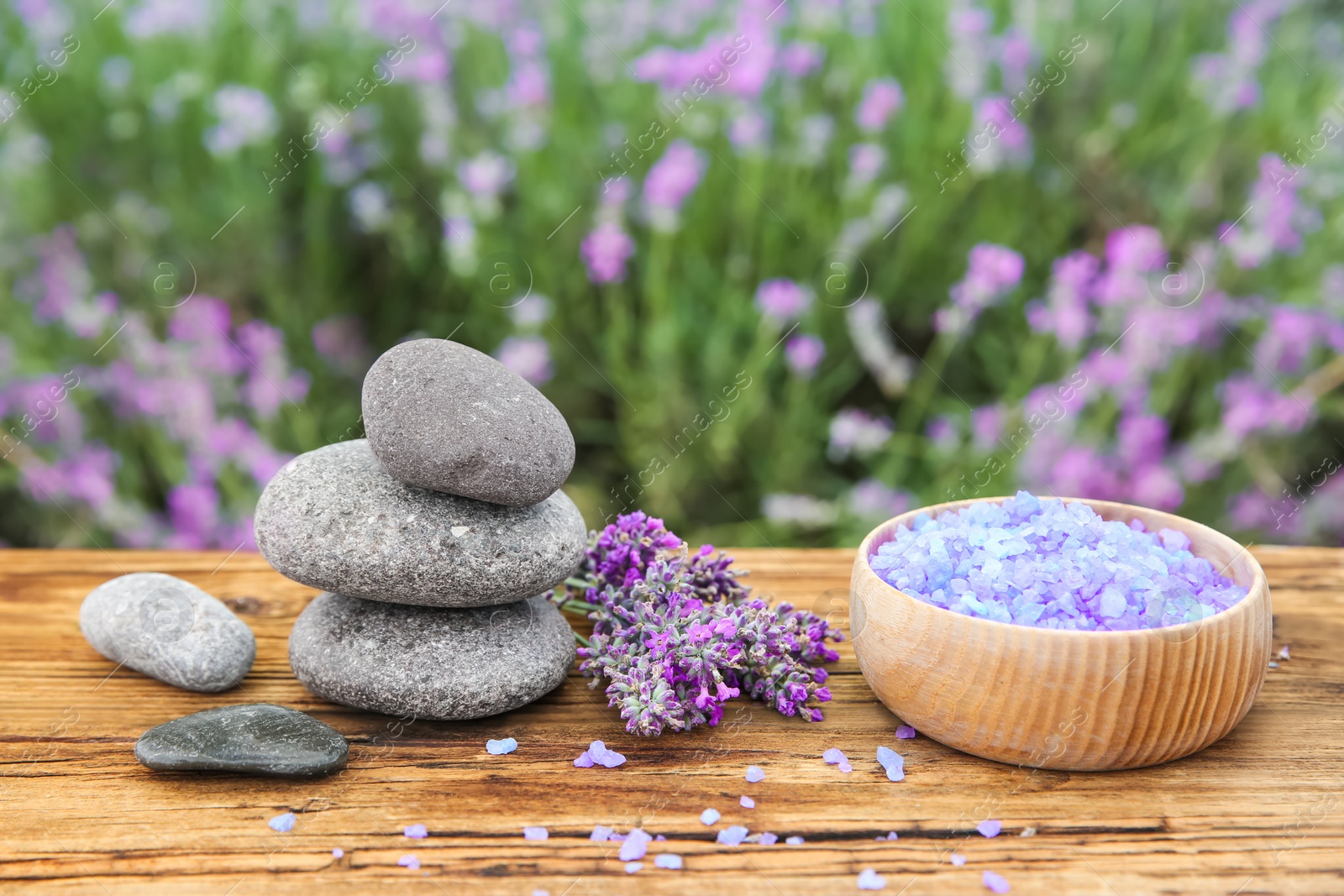 Photo of Spa stones, fresh lavender flowers and bath salt on wooden table outdoors, closeup