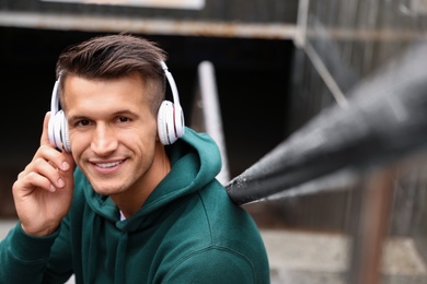 Photo of Portrait of handsome young man with headphones listening to music outdoors. Space for text