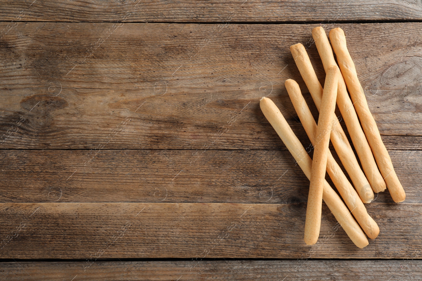 Photo of Delicious grissini sticks on wooden table, flat lay. Space for text