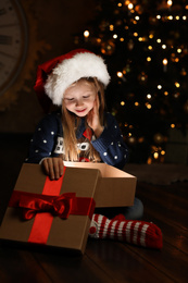 Photo of Cute child opening magic gift box near Christmas tree at night
