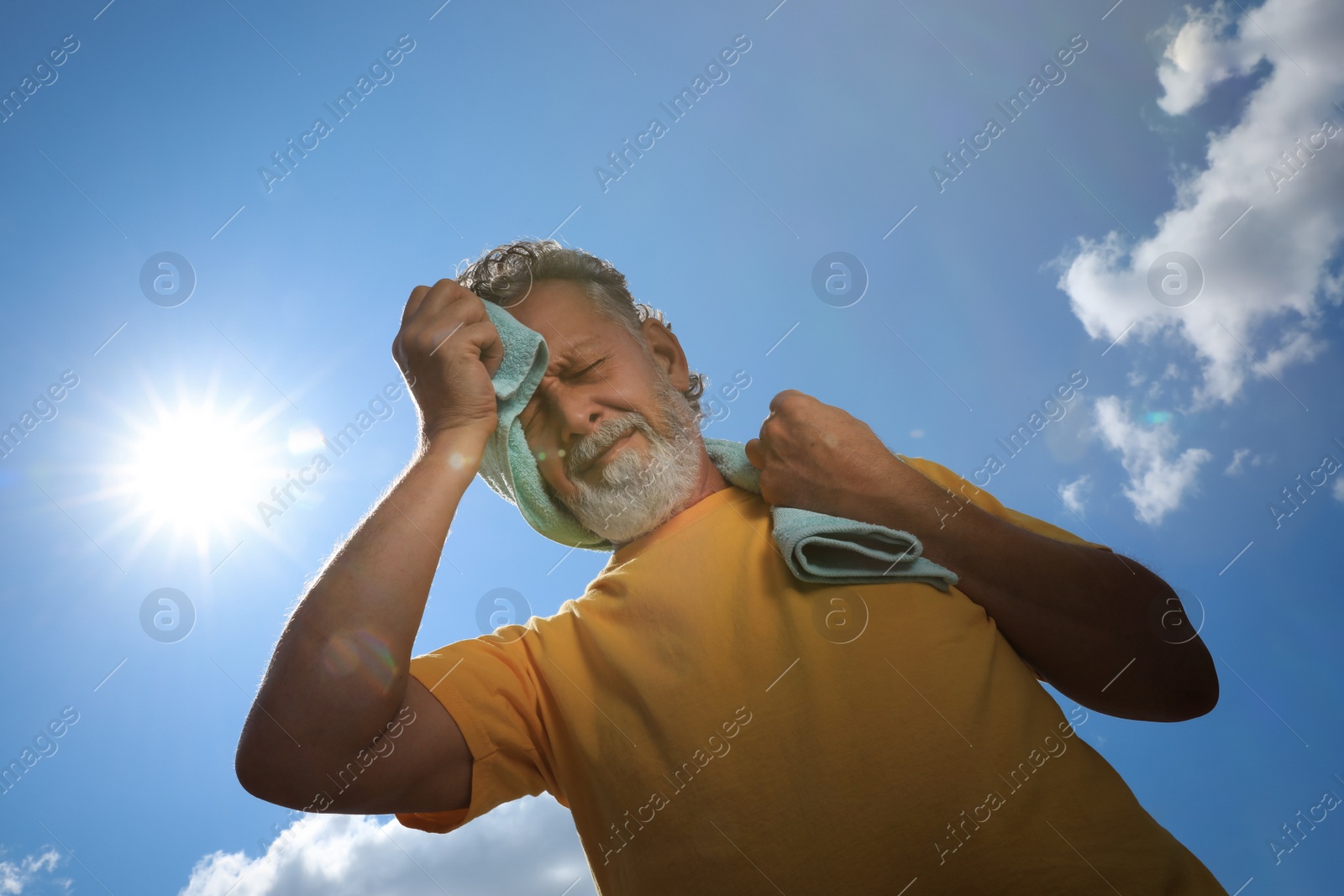 Photo of Senior man with towel suffering from heat stroke outdoors, low angle view