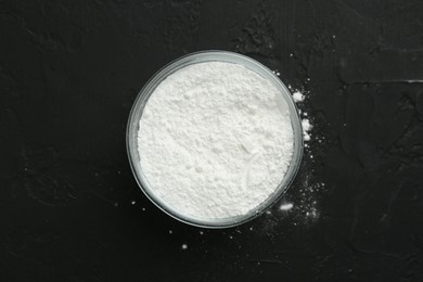 Photo of Baking powder in bowl on black textured table, top view