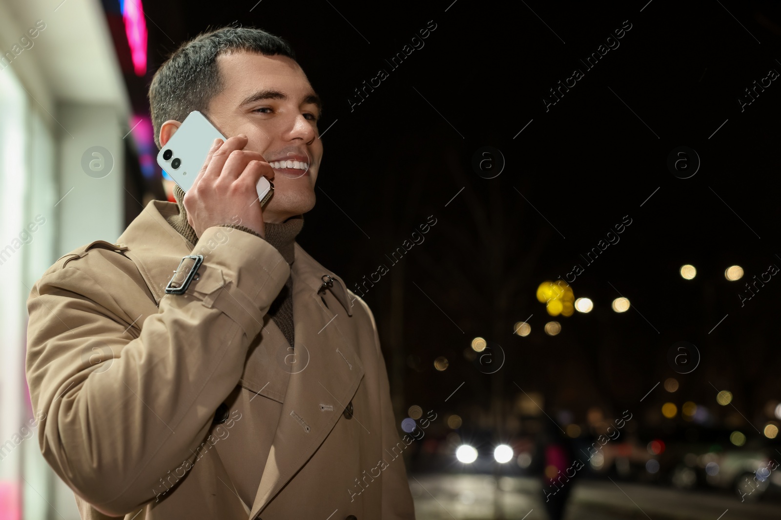Photo of Man talking by smartphone on night city street, space for text