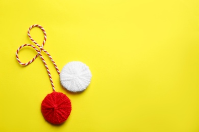 Photo of Traditional martisor on yellow background, top view with space for text. Beginning of spring celebration