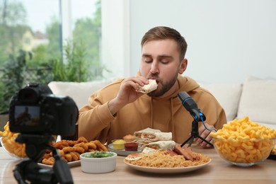 Food blogger recording eating show on camera in room. Mukbang vlog