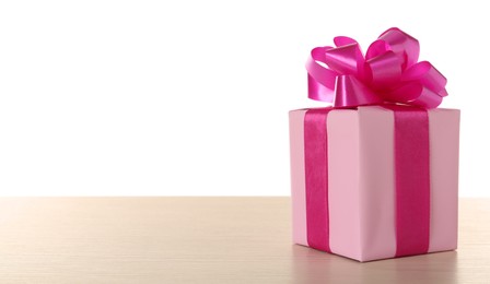 Photo of Beautifully wrapped gift box with pink bow on wooden table against white background, space for text