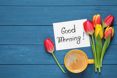 Photo of Message GOOD MORNING, tulips and coffee on blue  wooden table, flat lay. Space for text