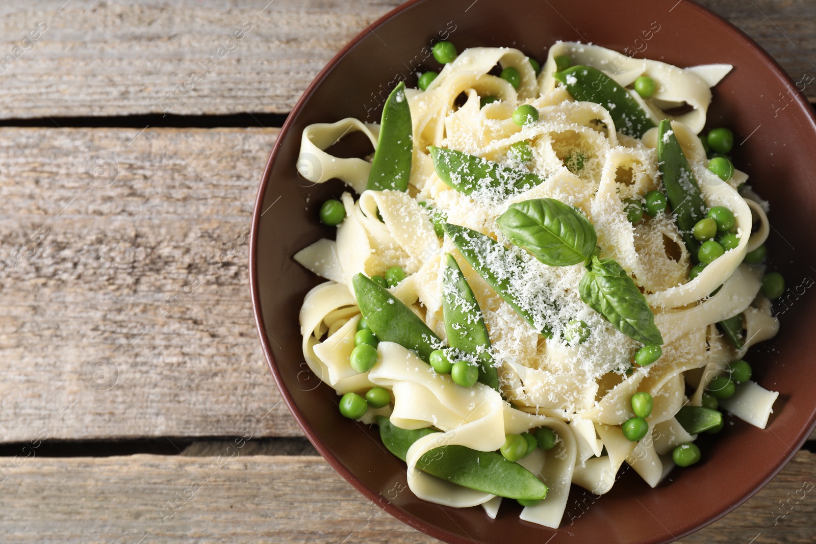 Photo of Delicious pasta with green peas and cheese on wooden table, top view. Space for text