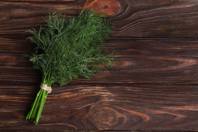 Photo of Bunch of fresh dill on wooden table, top view. Space for text