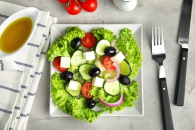 Photo of Tasty fresh Greek salad on grey table, flat lay