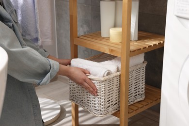 Photo of Woman holding storage box with towels indoors, closeup