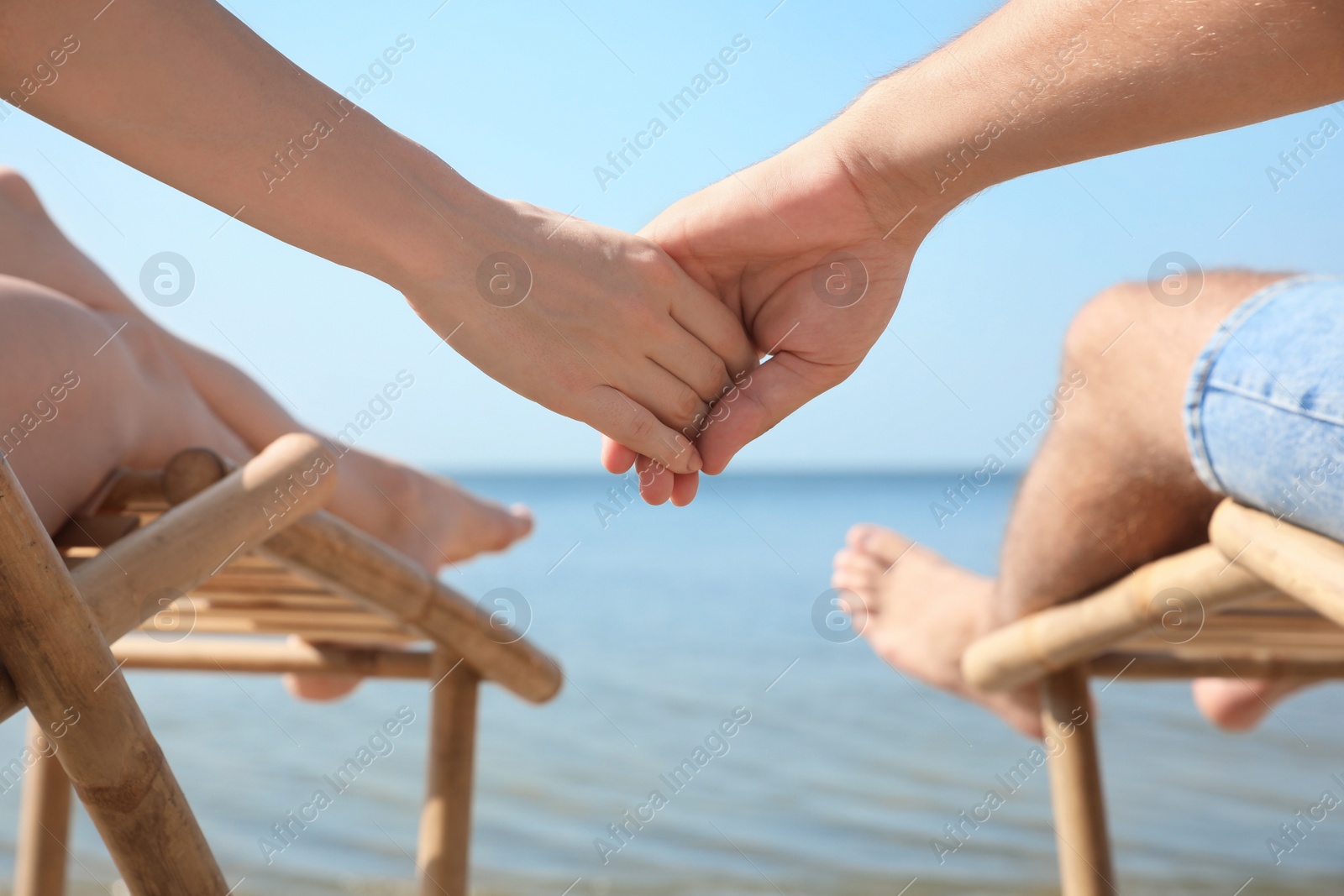 Photo of Young couple relaxing in deck chairs on beach near sea, closeup