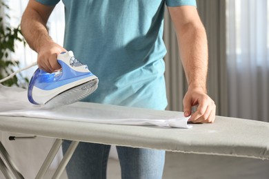 Photo of Man ironing clean shirt at home, closeup