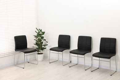 Many chairs near white wall in waiting area indoors