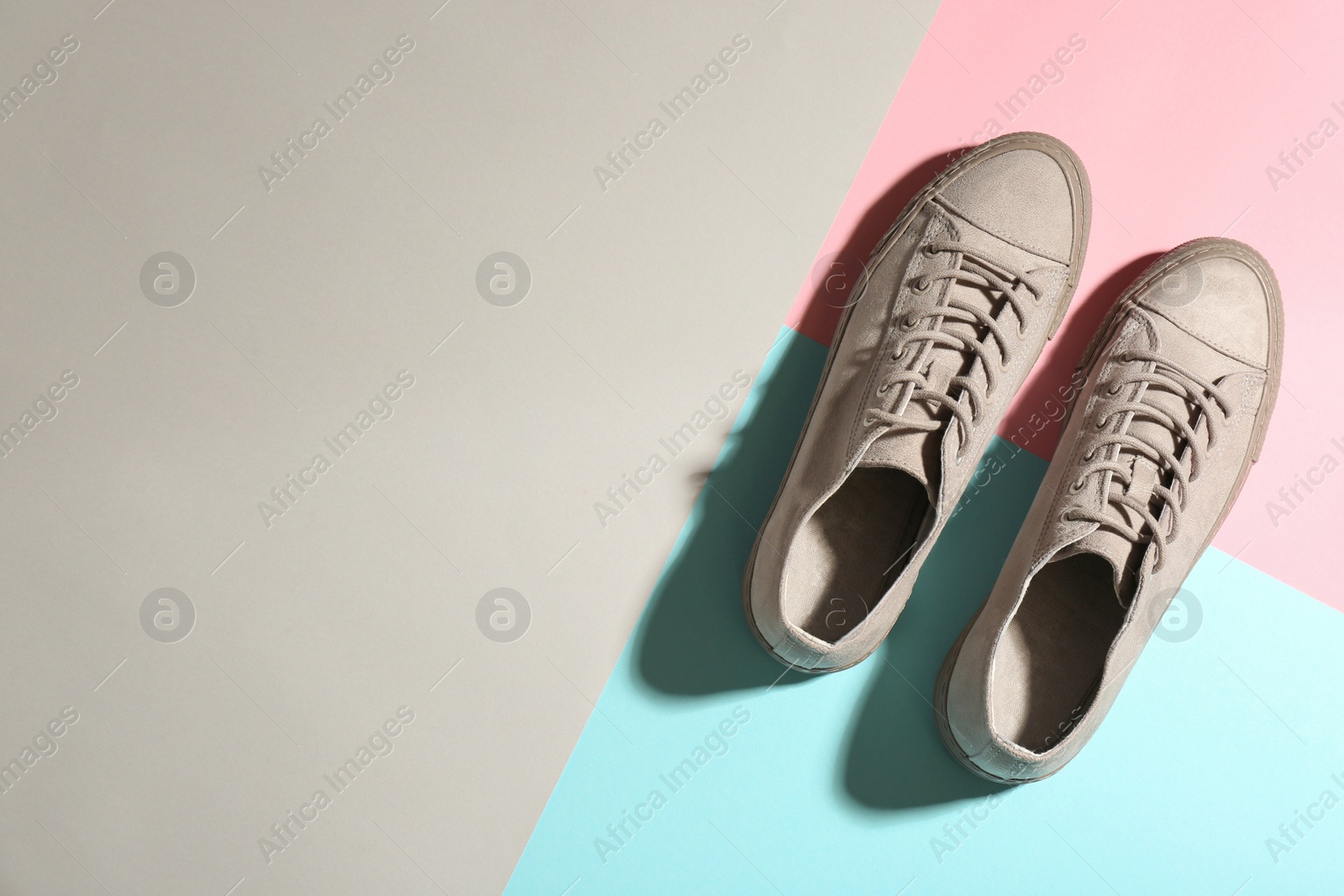 Photo of Pair of stylish sneakers on color background, top view with space for text