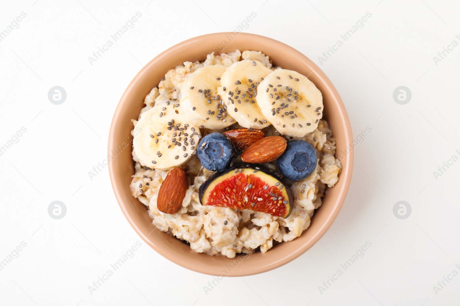 Photo of Bowl of oatmeal with blueberries, almonds, banana and fig pieces isolated on white, top view