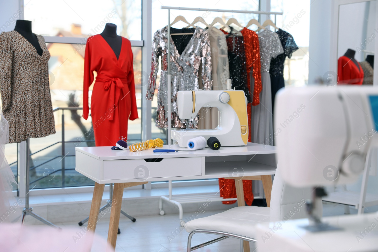 Photo of Dressmaking workshop interior with stylish female clothes and equipment