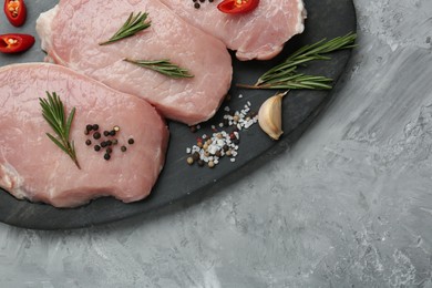 Photo of Pieces of raw pork meat, chili pepper and spices on grey textured table, top view. Space for text