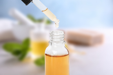 Little bottle with essential oil and dropper against blurred background 