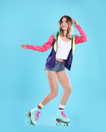 Young woman with retro roller skates on color background