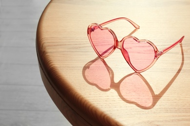 Photo of Stylish heart shaped sunglasses on wooden table. Space for text
