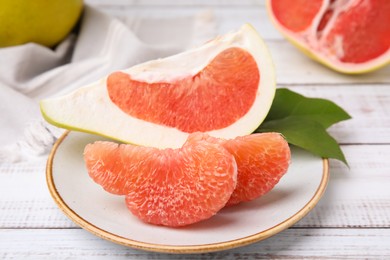 Photo of Tasty pomelo fruits on white wooden table, closeup