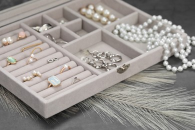 Photo of Jewelry box with many different accessories on grey table, closeup