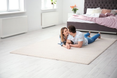 Lovely young couple lying on cozy carpet at home