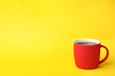 Red ceramic cup with hot aromatic coffee on color background