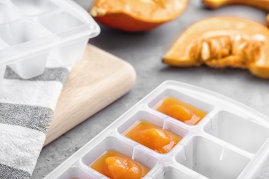 Photo of Ice cube tray with healthy baby food on gray table