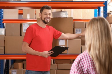 Woman and worker with clipboard near rack at post office